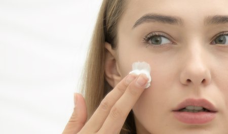 Une femme met de la crème pour peau grasse