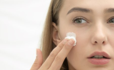 Une femme met de la crème pour peau grasse